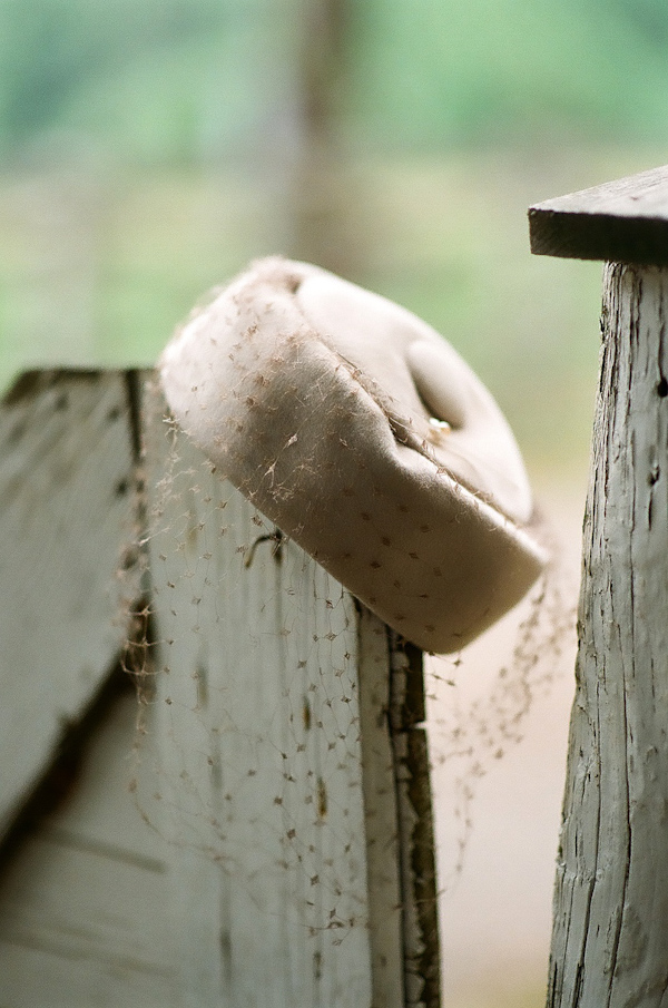 Vintage 1950's style woman's wedding hat hanging off old white battered fence post -photo by North Carolina wedding photographer Richard Israel 
